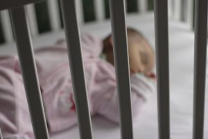 Photo of baby sleeping alone on their back in a crib