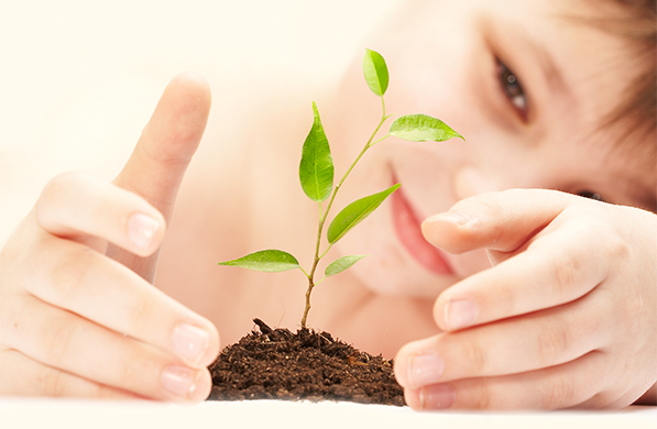 Photo of boy holding a sprouted plant in soil denoting the Faith-Based Symposium theme of