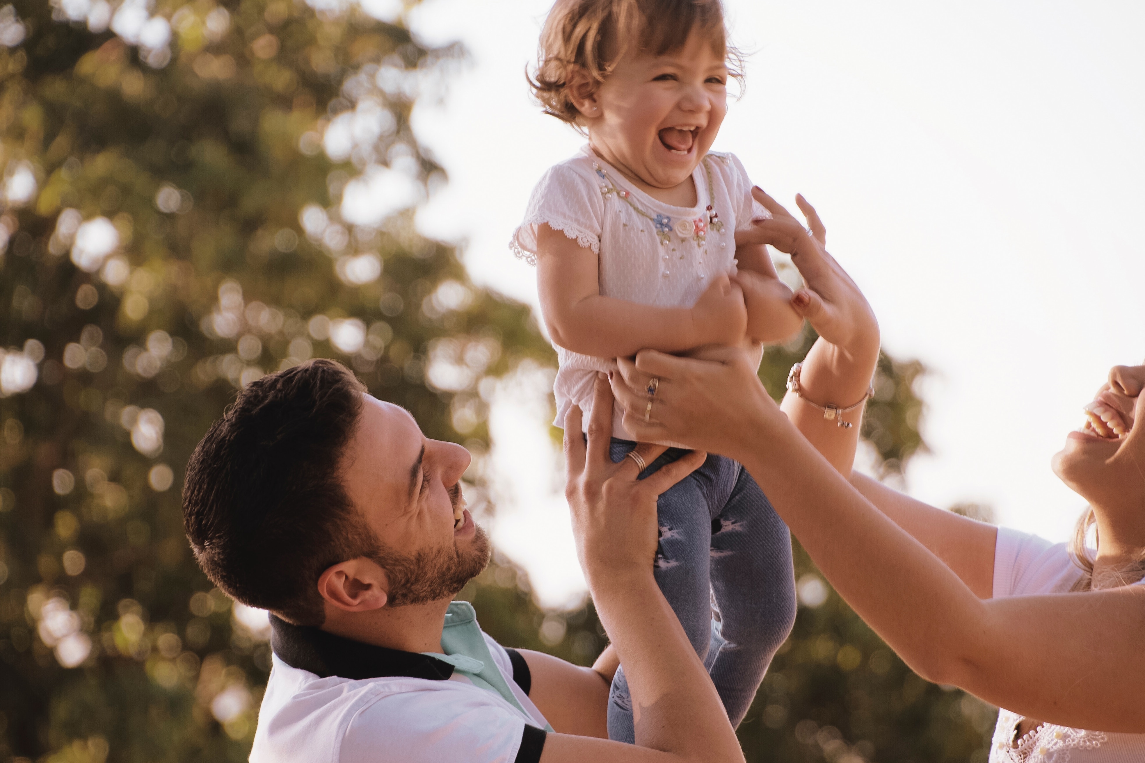 Mother and father playing with their son by tossing him in the air and catching him