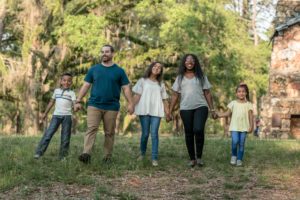 Mother and father with three children walking and holding hands in a park
