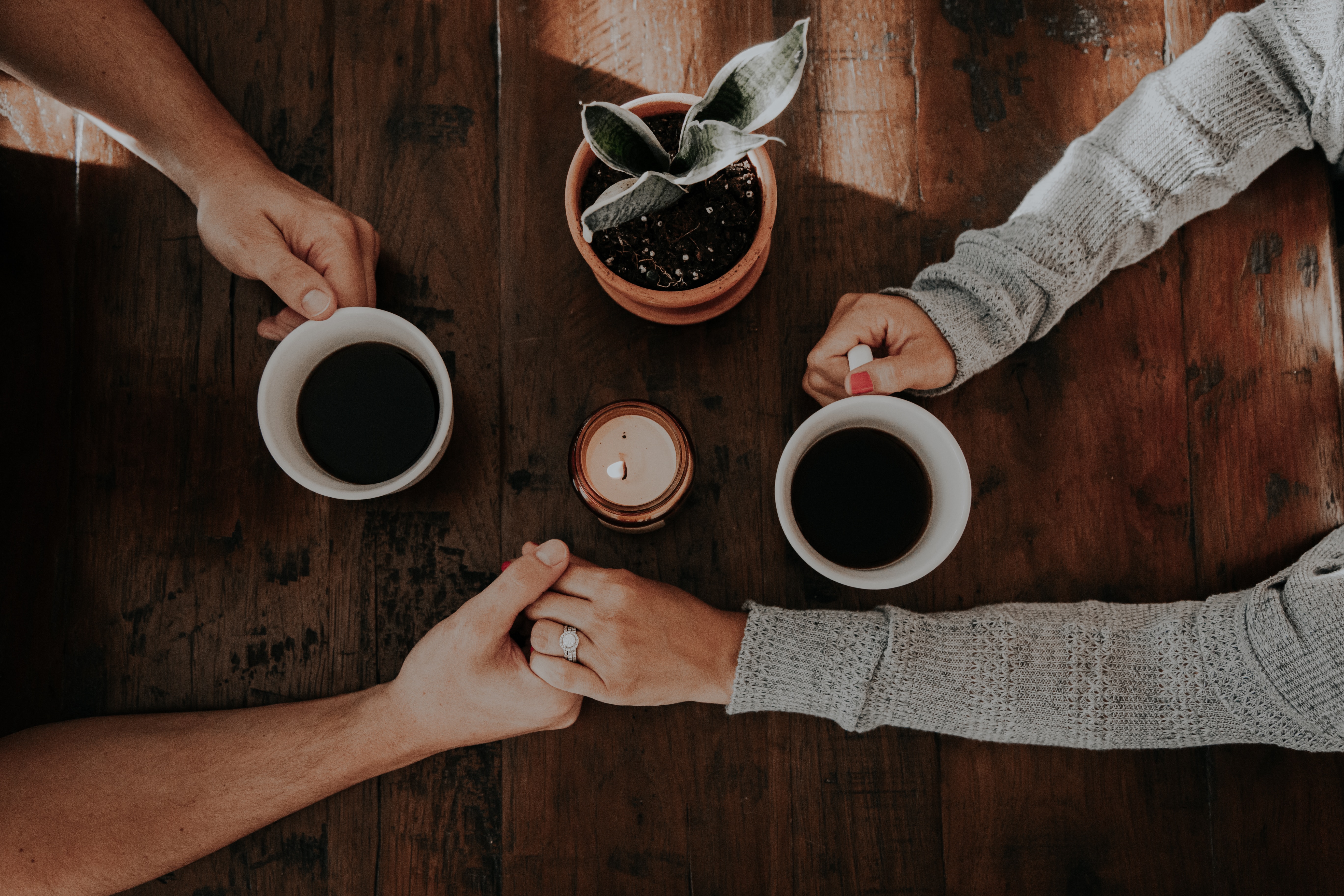 Couple holding hands on table while drinking coffee