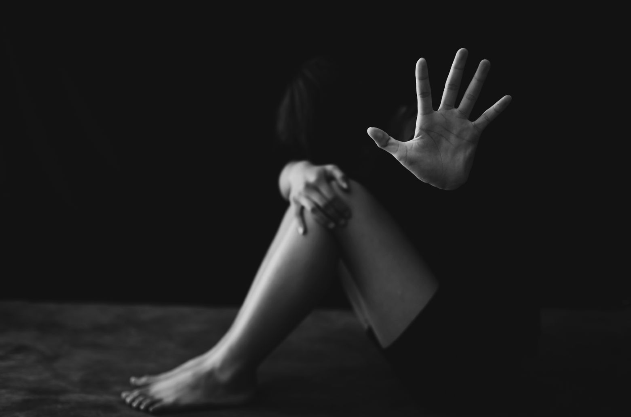 Black and white photo of woman holding hand up to camera