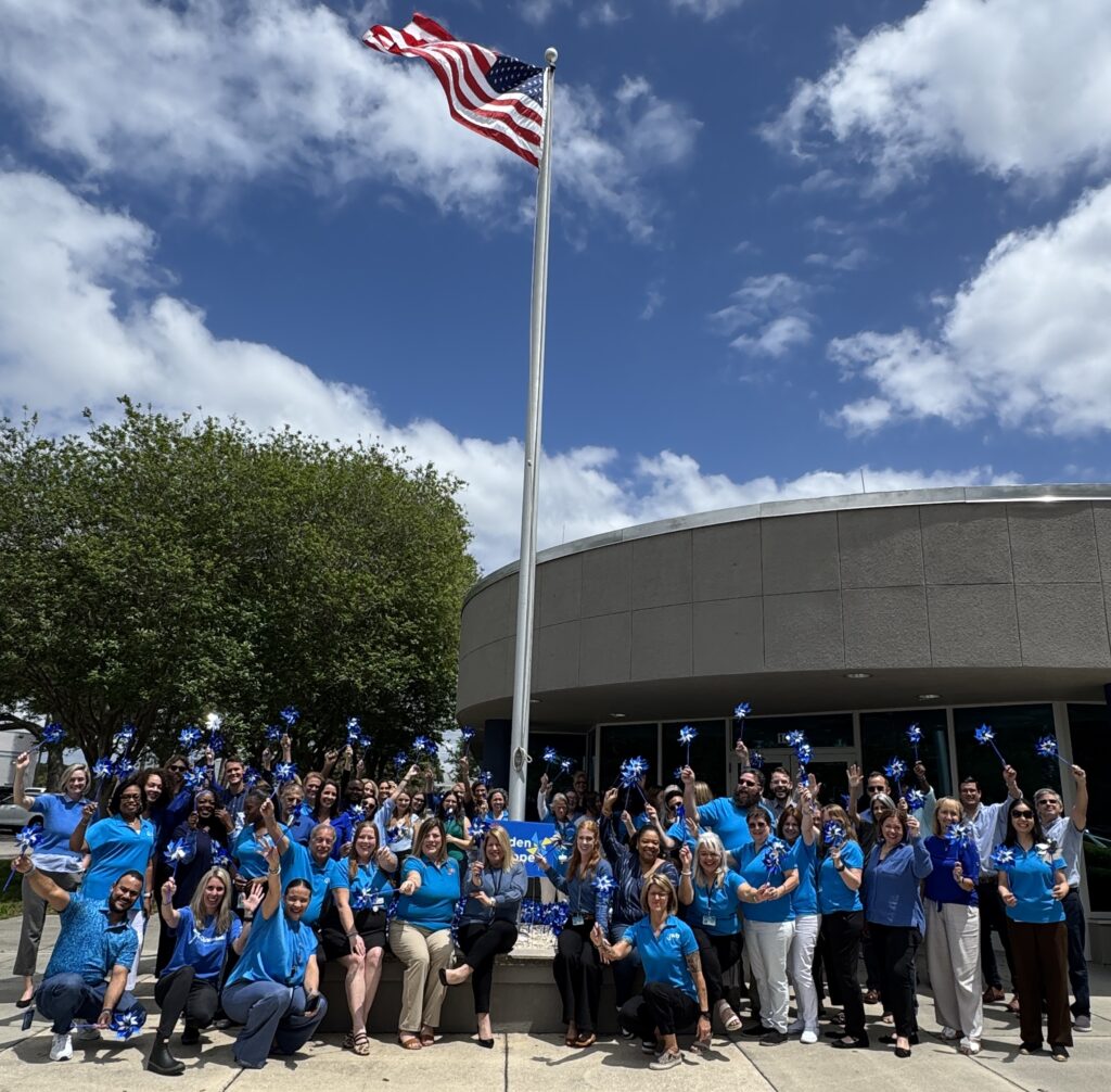 JWB staff posed in front of our office and pinwheel garden for a candid Wear Blue Day photo
