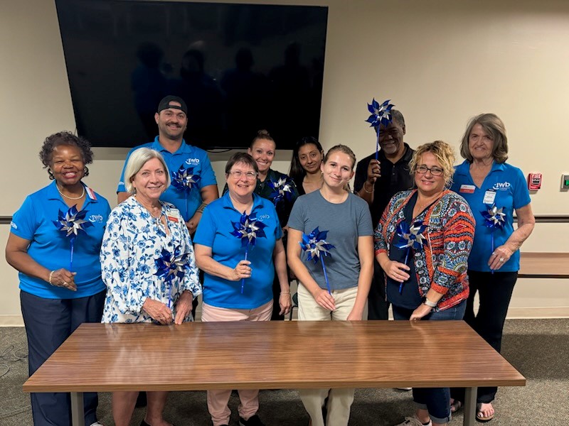 JWB's North County Community Council Members posed in blue and with pinwheels for Child Abuse Prevention Month